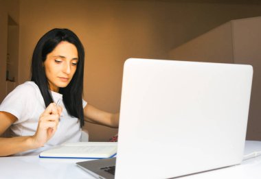 Young long dark haired georgian woman takes notes in her living room