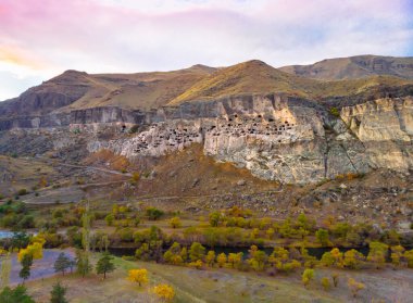 Aerial perspective of Vardzia-cave city from above with paravani river and autumn nature in foreground. Historical unesco sites Georgia.