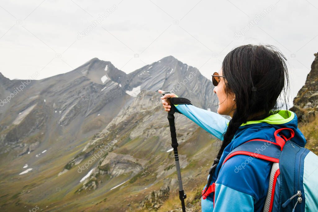 Close up young caucasian woman hiker stand on viewpoint show destination mountains point finger left outdoors destination. Guide young woman in mountains