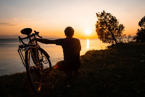 Ciclista Abbraccia Sua Bicicletta Godersi Tramonto Sul Tranquillo Lago Calmo — Foto Stock