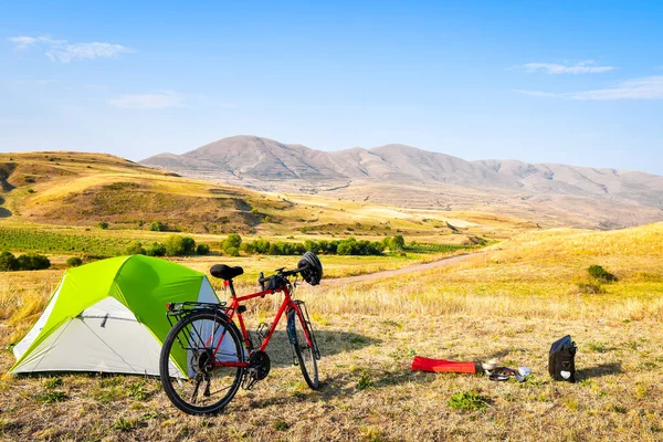 Panorama of unloaded touring red bicycle by green tent. Camping and bicycle touring concept Travel around Armenia by bicycle in mountains in autumn