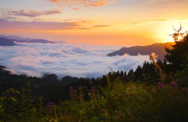 Adjara bölgesinde bulutların üzerinden geçen ve ufukta güneş görünen dramatik günbatımı zamanı. Bulutlar üzerinde sersemletici bir günbatımı arkaplanı.
