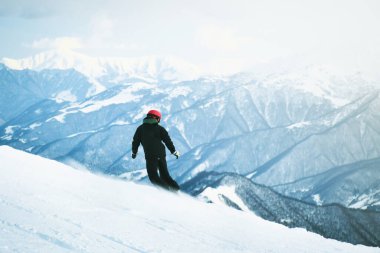 Genç snowboardcu tepeden aşağıya doğru hızla donmuş hareketli kafkas dağlarında tek başına iniyor.
