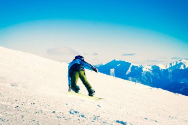 Genç snowboardcu tepeden aşağıya doğru hızla donmuş hareketli kafkas dağlarında tek başına iniyor.