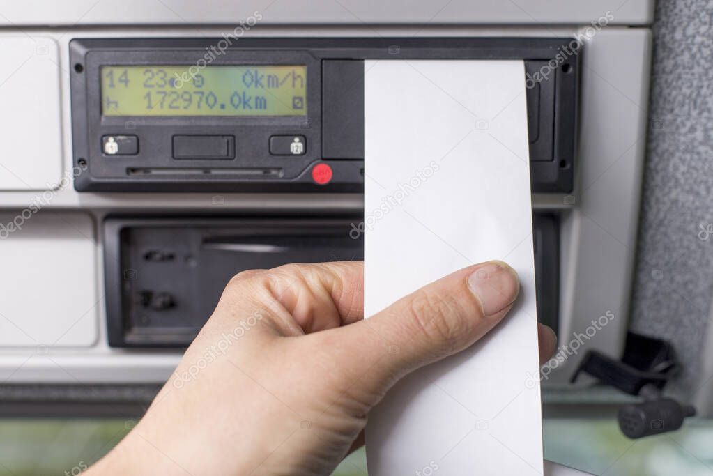 Close up of a driver holding empty printed day shift against a digital tachograph