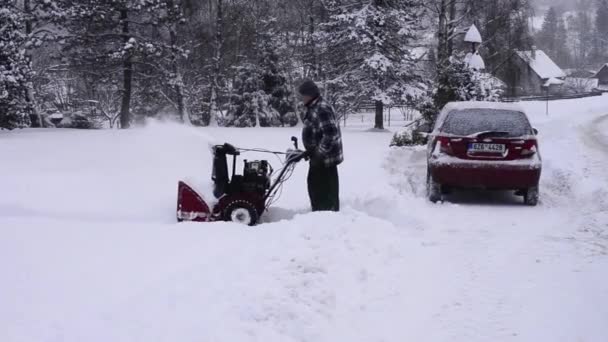 Becva, Czech Rep Jan 22nd 2022. Человек убирает снег с подъездной дорожки снегоочистителем — стоковое видео