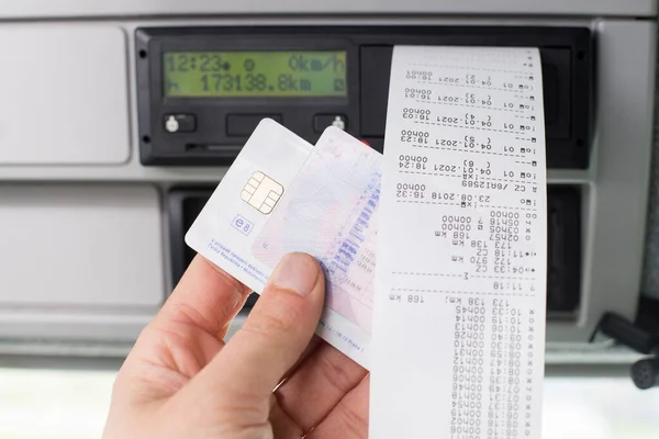 Close up of a driver holding printed day shift in focus together with drivers licence and digital tachograph card . — Zdjęcie stockowe