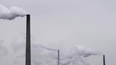 Gri bir günde birden fazla fabrika bacası tütüyor. Monokromatik.