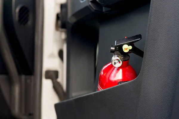 Red fire extinguisher in a black truck door. — Stock Photo, Image