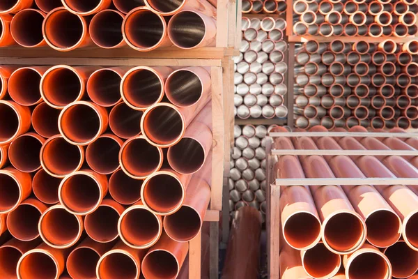 Background of orange plastic sewage pipes used at the building site. Texture and pattern of plastic drainage pipe. Light through tubes