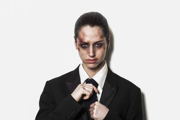 Beaten up girl wearing coat and tie and looking — Stock Photo, Image