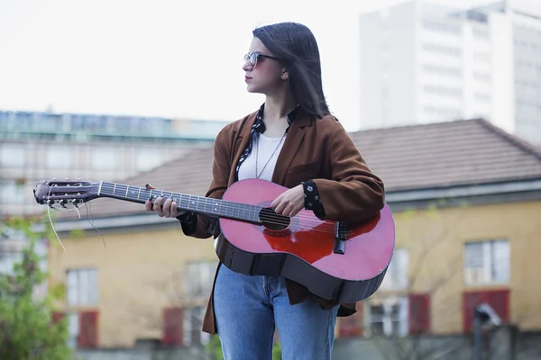 Девушка играет на гитаре в городской сцене — стоковое фото