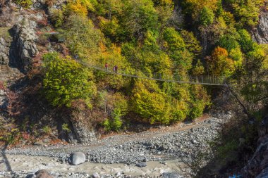 Turistler vadi üzerindeki asma köprü boyunca yürüyorlar. Azerbaycan 'daki Lahij köyü