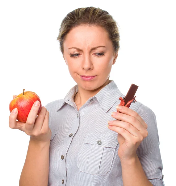 Diyet kavramı: kadın meyve ve çikolata arasında seçim yapma — Stok fotoğraf