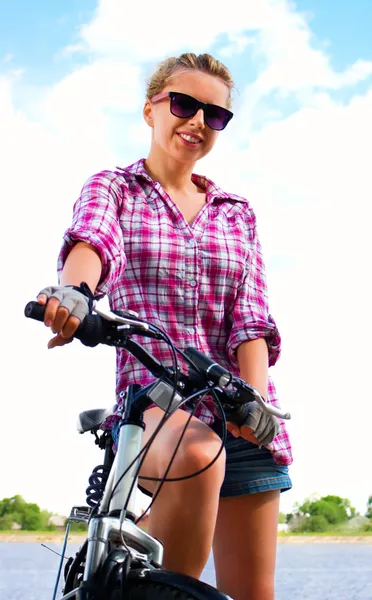 Junge glückliche Frau sitzt auf ihrem Fahrrad, Outdoor-Shooting — Stockfoto