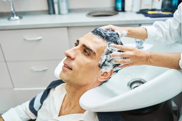 Mężczyzna odpoczywa podczas mycia włosów w salonie piękności — Zdjęcie stockowe