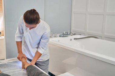 Odaklanmış fotoğraf osteopat rehabilitasyon masajı yapıyor.