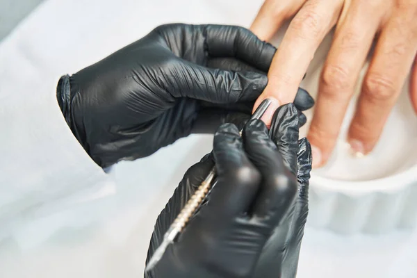 Esthéticienne poussant la peau à la base de l'ongle avec poussoir cuticule — Photo