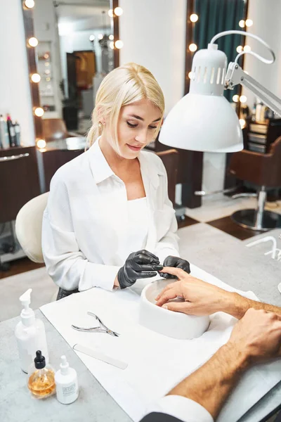 Skönhetsterapeut tar bort död hud från nageln med nagelband pusher — Stockfoto