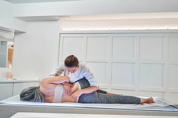 Osteopath streckt Rücken und Bein im Reha-Zentrum — Stockfoto