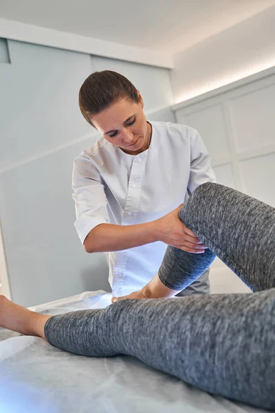 Serieuze vrouwelijke therapeut doet de behandeling van massage voor cliënt — Stockfoto