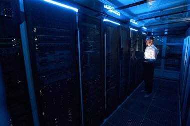 Dikkatli sistem yöneticisi dizüstü bilgisayarla sunucu rafına bakıyor