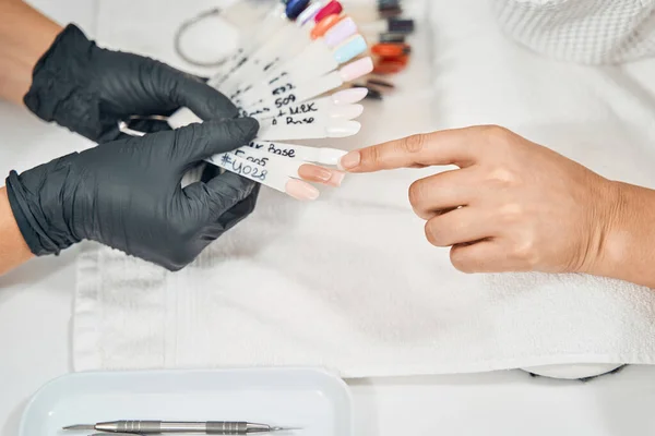 Primer plano de la mujer apuntando al esmalte de uñas desnudo —  Fotos de Stock