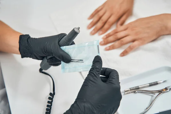 Foto focada em prego mestre segurando broca para manicure — Fotografia de Stock