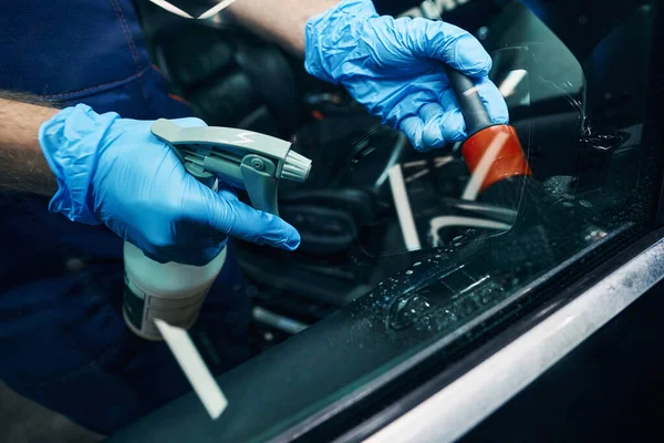 Mechanic is spraying window with cleaning detergent — Stock Photo, Image