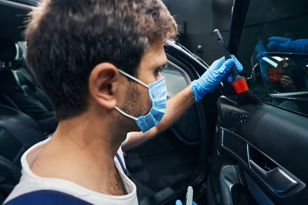 Worker cleaning panel under car window with brush — Stock Photo, Image