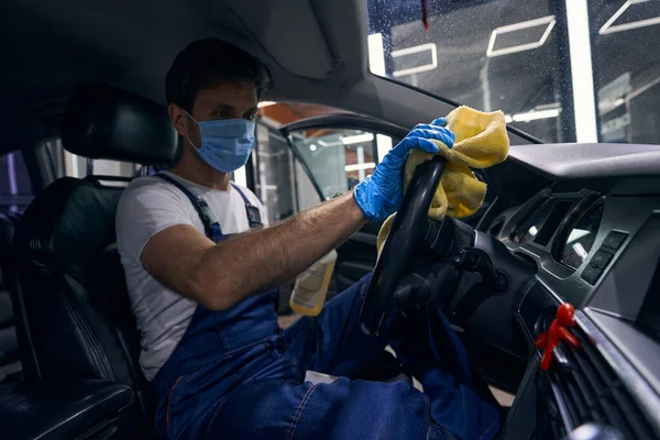 Caucasian auto repair mechanic wiping automobile driving wheel — Stock Photo, Image