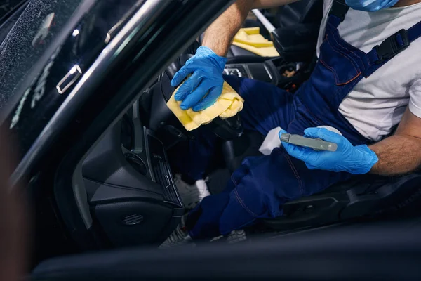 Person wiping driving wheel with yellow towel — Stock Photo, Image