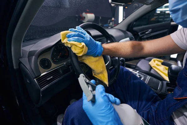 Paño amarillo en la mano del trabajador que limpia el volante — Foto de Stock