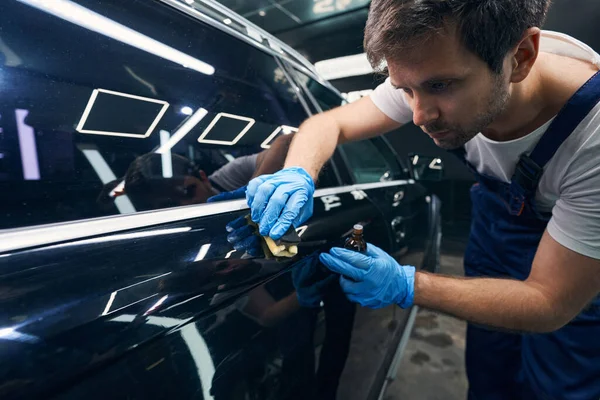 Trabajador atento mancha manchas en la superficie del automóvil con recubrimiento de cerámica —  Fotos de Stock