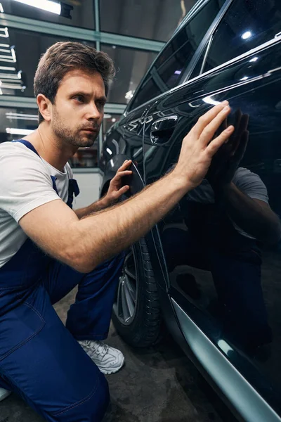 Muž automobilový technik hledá škrábance na autě — Stock fotografie
