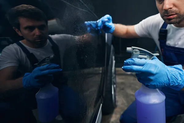 Mecánico de coche usando spray de limpieza en la puerta del automóvil — Foto de Stock