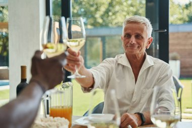 Ciddi bir adam arkadaşlarıyla kadeh tokuşturuyor.