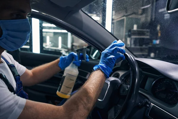 Male wiping steering wheel of car from cleaning fluid — Stock Photo, Image