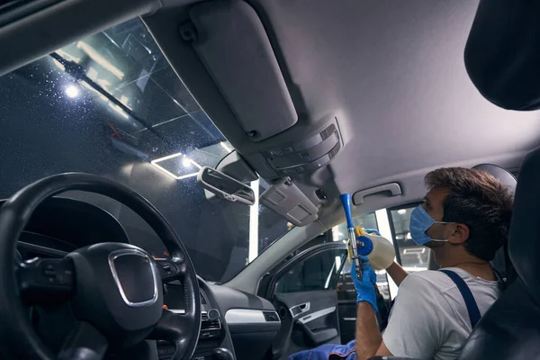 Técnico de servicio de coche masculino que cubre el techo de la cabina con productos químicos — Foto de Stock