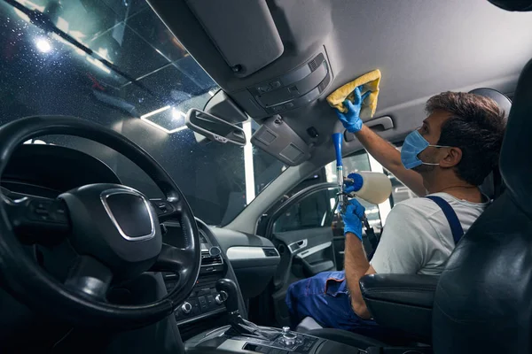 Hombre con aparato de limpieza en seco que cuida el techo del coche —  Fotos de Stock