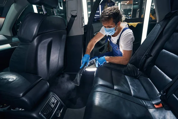 Limpieza de vapor masculino debajo de los asientos traseros del automóvil —  Fotos de Stock