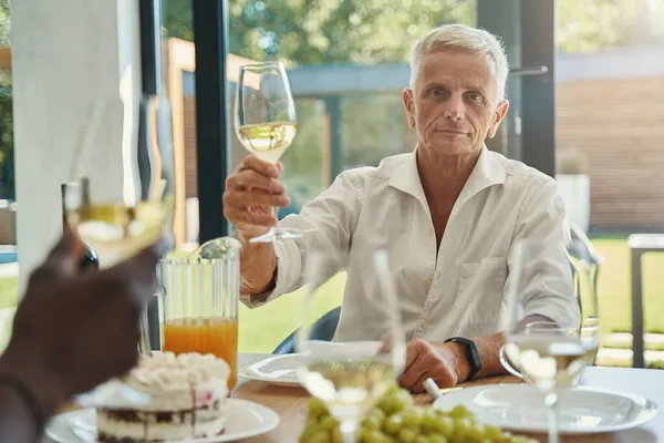 Чоловік тримає келих вина, сидячи за столом — стокове фото