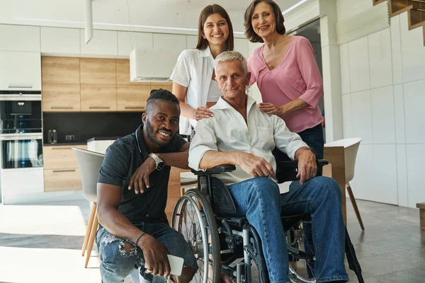 Osoby wspierające mężczyznę z niepełnosprawnością fizyczną w domu — Zdjęcie stockowe