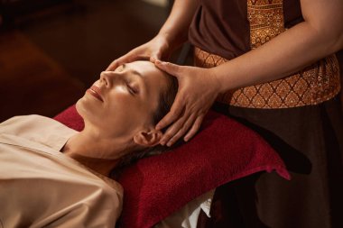 Deneyimli masöz, hasta kafasındaki akupuanları uyarır.