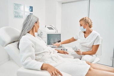 Dikkatli sarışın uzman bilgisayar ekranını işaret ediyor