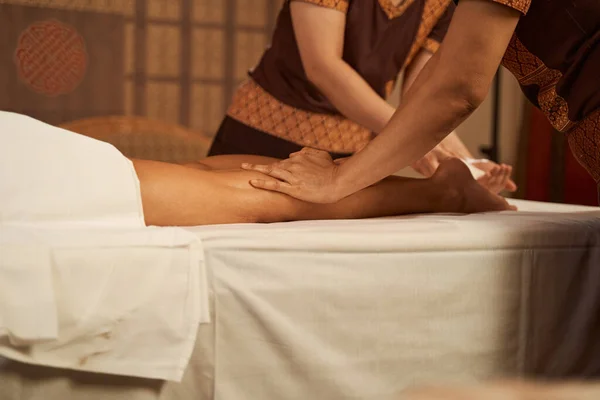 Doświadczeni masażyści wykonujący masaż czterema rękami nóg u klienta — Zdjęcie stockowe