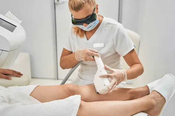 Profesionální kosmetolog provádějící laserovou proceduru odstraňování chloupků — Stock fotografie