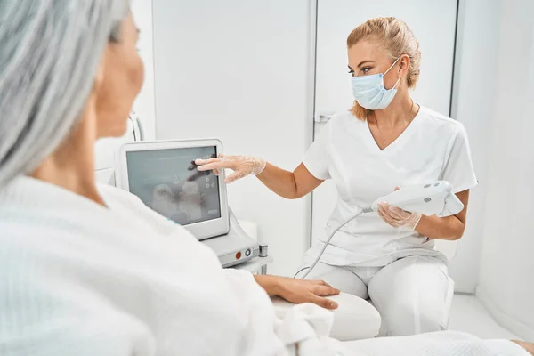 Kompetent salongsarbetare som rådfrågar patienten före ingreppet — Stockfoto