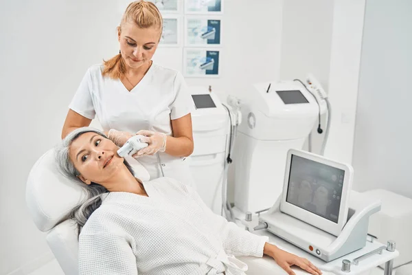 Concentrated beauty master doing face lifting procedure — Stock Photo, Image