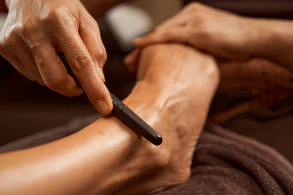 Beoefenaar met behulp van reflexologie stok tijdens Thaise voet massage sessie — Stockfoto